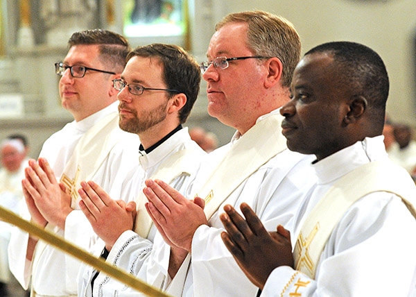 Newly ordained priests Cole Webster, Luke Uebler, Martin Gallagher and Robert Agbo listen to Bishop Richard Malone as he speaks during  the Ordination Mass at St. Joseph Cathedral. (Dan Cappellazzo/Staff Photographer)